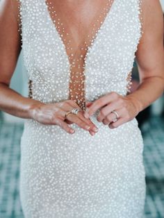 a woman in a white dress holding onto her wedding ring