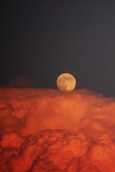 the full moon is seen above some clouds