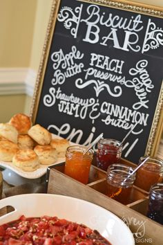 a table topped with lots of food next to a chalkboard sign that reads biscuit bar - adorable idea for a brunch party or shower