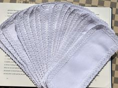 five pieces of white cloth sitting on top of a checkered tablecloth covered in papers