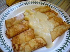 some food is on a white plate with blue and green designs around it, including crepes