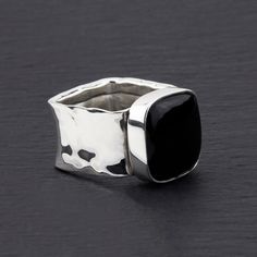 Make a bold statement with this square band black obsidian ring. The sleek and substantial design of this ring highlights the allure of the black obsidian square, adding a touch of mystery and elegance. With its thick hammered silver band, this ring is both modern and timeless. Elevate your style with the dramatic presence of this piece, perfect for those who appreciate a confident and distinctive look.  See a matching necklace. Gemstone - Black Obsidian 925 Sterling silver Hammered finish The s Chunky Rings Black, Modern Black Cabochon Rings, Black Obsidian Gemstone Ring, Handmade Black Crystal Ring In Sterling Silver, Black Obsidian Ring, Black Brutalist Sterling Silver Jewelry, Obsidian Ring, Chunky Silver Rings, Obsidian Stone