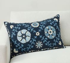 a blue and white pillow sitting on top of a white couch next to a wall