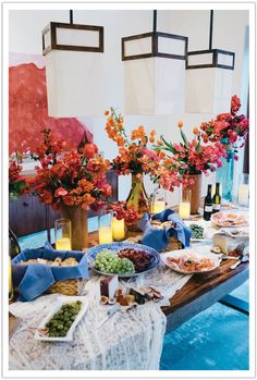 a table topped with lots of food next to vases filled with flowers and candles