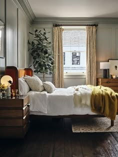 a white bed sitting next to a window in a room with wooden floors and walls