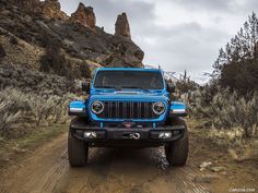 a blue jeep driving down a dirt road