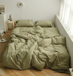 an unmade bed sitting in a bedroom next to a white wall and wooden floor