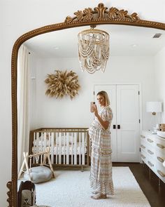 a woman taking a selfie in front of a mirror with a baby crib