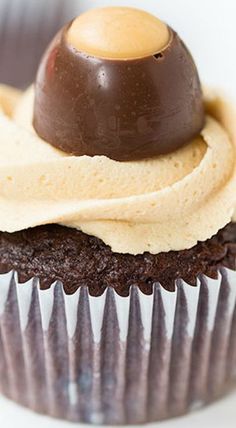 a chocolate cupcake topped with cream frosting and a caramel top on a white plate