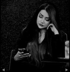 a woman sitting at a table looking at her cell phone