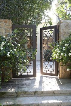 an open door leading to a garden with white flowers and greenery on either side