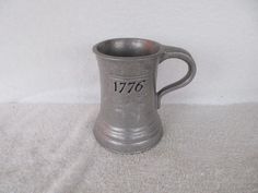 an old pewware mug with the number seventy on it's side is sitting on a white surface