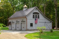 a white barn with an american flag on the roof