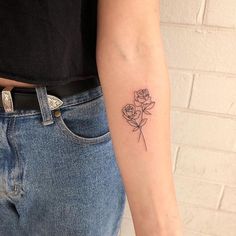 a woman with a tattoo on her arm holding a flower in one hand and a rose in the other