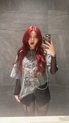 a woman with red hair is taking a selfie in front of a gray wall