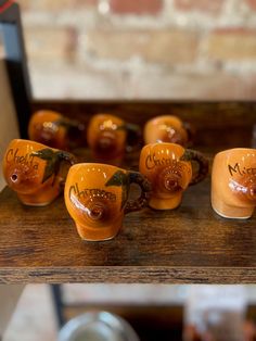 there are many small orange cups on the shelf in front of some other glassware