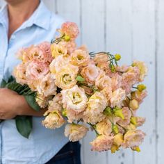 a man holding a bouquet of flowers in his hands and wearing a blue button up shirt