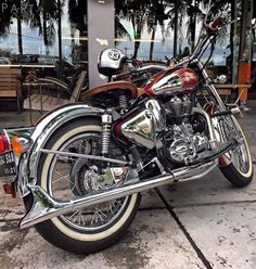 two motorcycles parked next to each other in front of a building with palm trees behind them