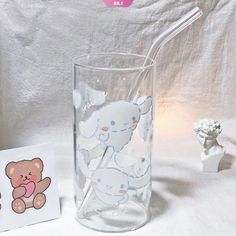 there is a glass with a straw in it next to a card and a teddy bear