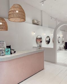 the interior of a hair salon with white walls and wood flooring, round mirrors on the wall