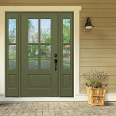 a green front door with two sidelights and potted plants on the outside steps