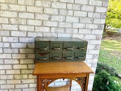 an old fashioned stove sitting on top of a wooden table next to a brick wall