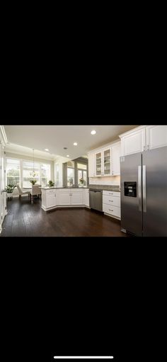 an empty kitchen with white cabinets and wood floors