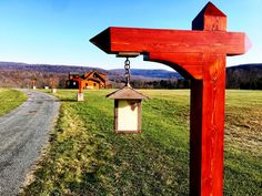 a red wooden cross hanging from the side of a road