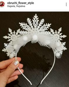 a hand holding a white headband with snowflakes on it