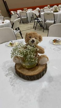 a teddy bear sitting on top of a tree stump with baby's breath in it