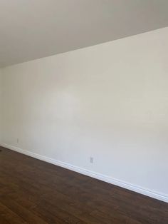 an empty room with hard wood floors and white walls