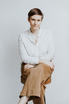 a woman sitting on top of a chair wearing white shirt and khaki pants