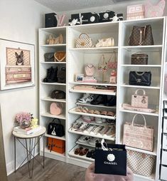 a white closet filled with lots of purses and handbags next to a table