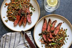 two white plates topped with steak and lentils