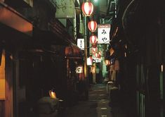 an alley way with lanterns hanging from the ceiling