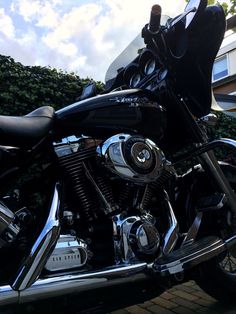 a black motorcycle parked on the side of a road next to a tree and building