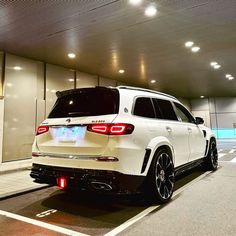 the rear end of a white suv parked in a parking garage with its lights on