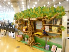 a tree with books on it in a room filled with tables, chairs and desks