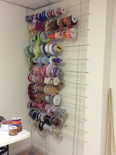 there is a rack with many different types of thread spools hanging on the wall