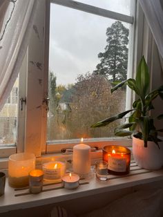 candles sit on a window sill in front of a large window