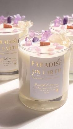 three candles with flowers on them sitting next to each other in glass containers that say paradise on earth