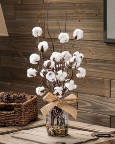 a glass jar filled with cotton flowers on top of a table next to a basket