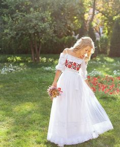 a woman in a white dress is walking through the grass