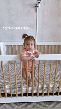 a baby girl standing in her crib with the caption, a day in the life of now