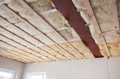 an unfinished room with wood beams and insulation on the ceiling, in front of a window