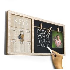 a hand holding a chalkboard with magnets on it and a key board attached to the wall