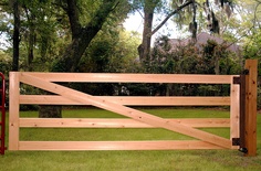 a wooden gate in the middle of a grassy area