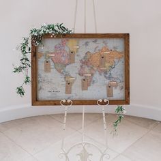 a map hanging on a wall with clothes pins attached to it and some greenery