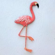 a pink flamingo standing on one leg with its legs spread out and it's head turned to the side