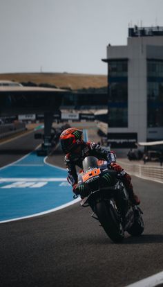 a man riding a motorcycle on top of a race track next to a tall building